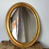 Oval-shaped wooden mirror in gold color