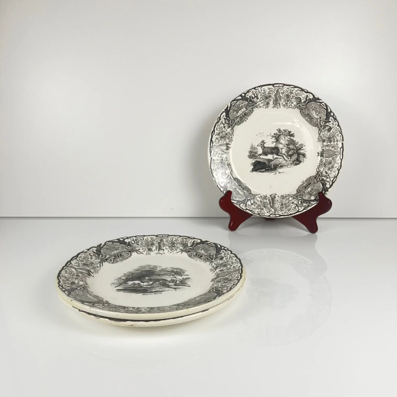 Set of three antique Sarreguemines U&C plates with hunting decoration from 1850 - 19th century black earthenware featuring a doe, chamois, and fox.
