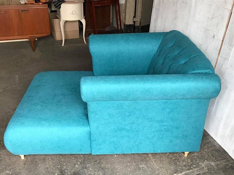 Mid-century turquoise blue fabric sofa with solid oak legs and tufting.