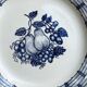Assiette en céramique blanche avec un motif de fruits bleus.