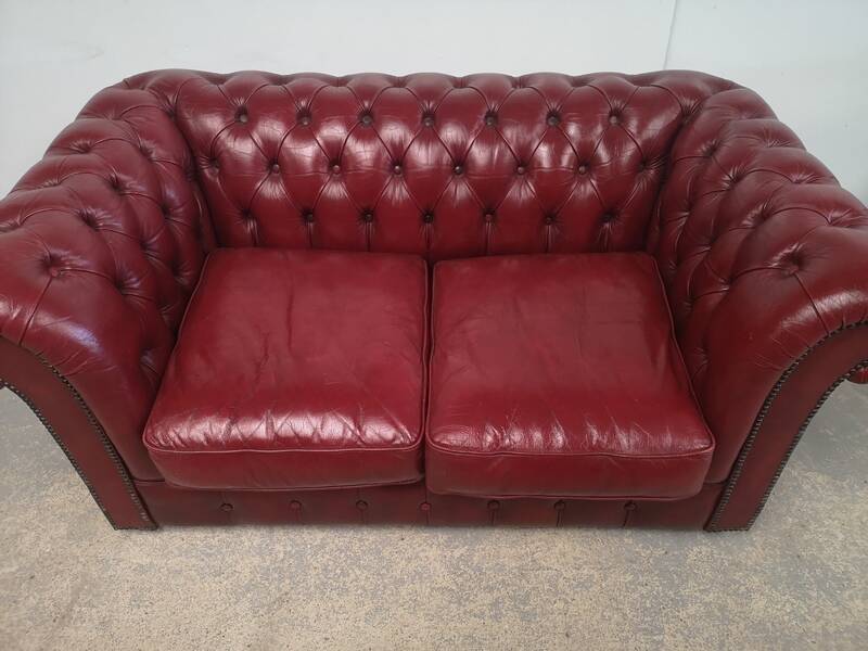 Red two-seater chesterfield sofa