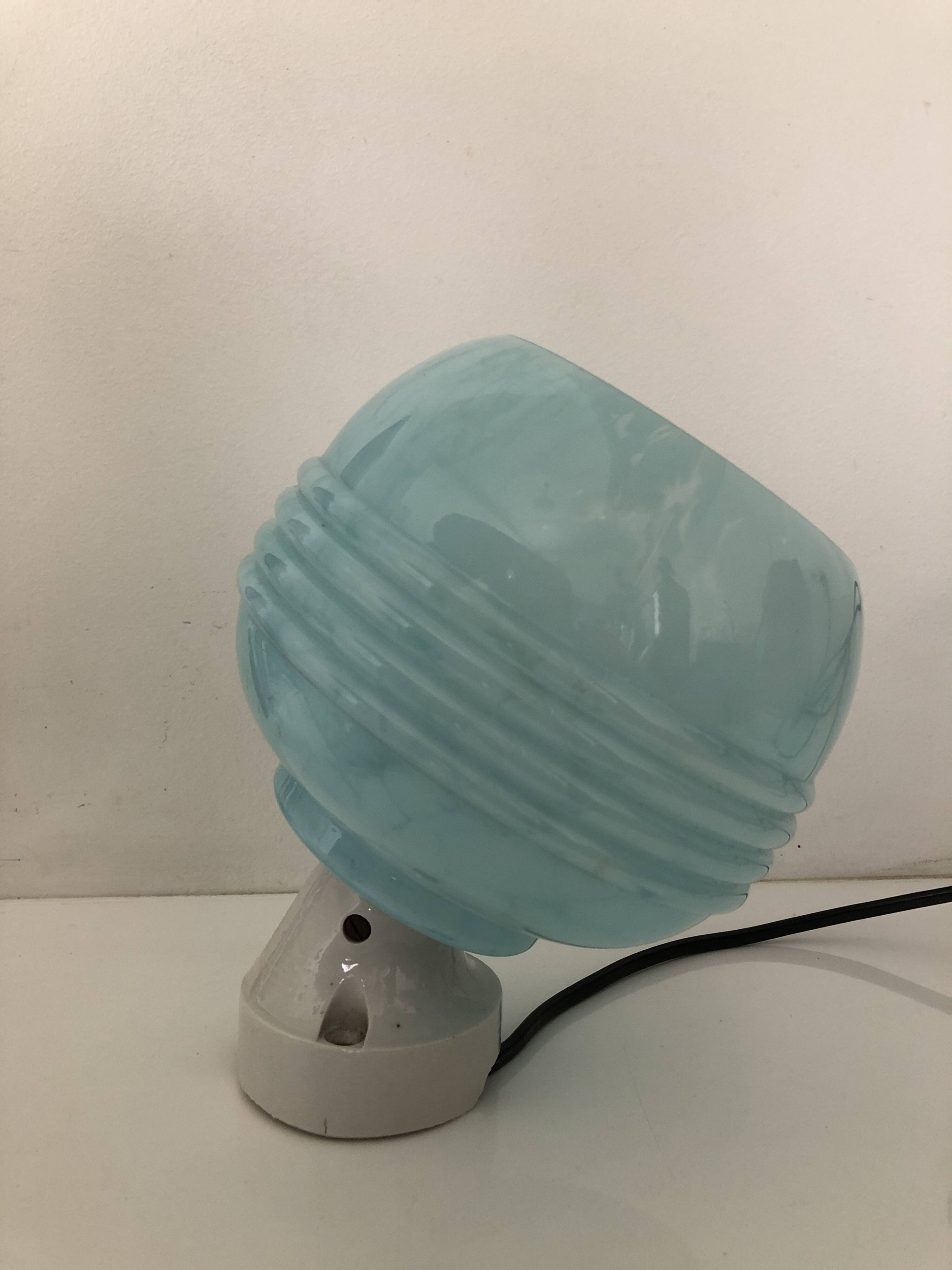 Wall light in ceramic with a light blue glass globe.