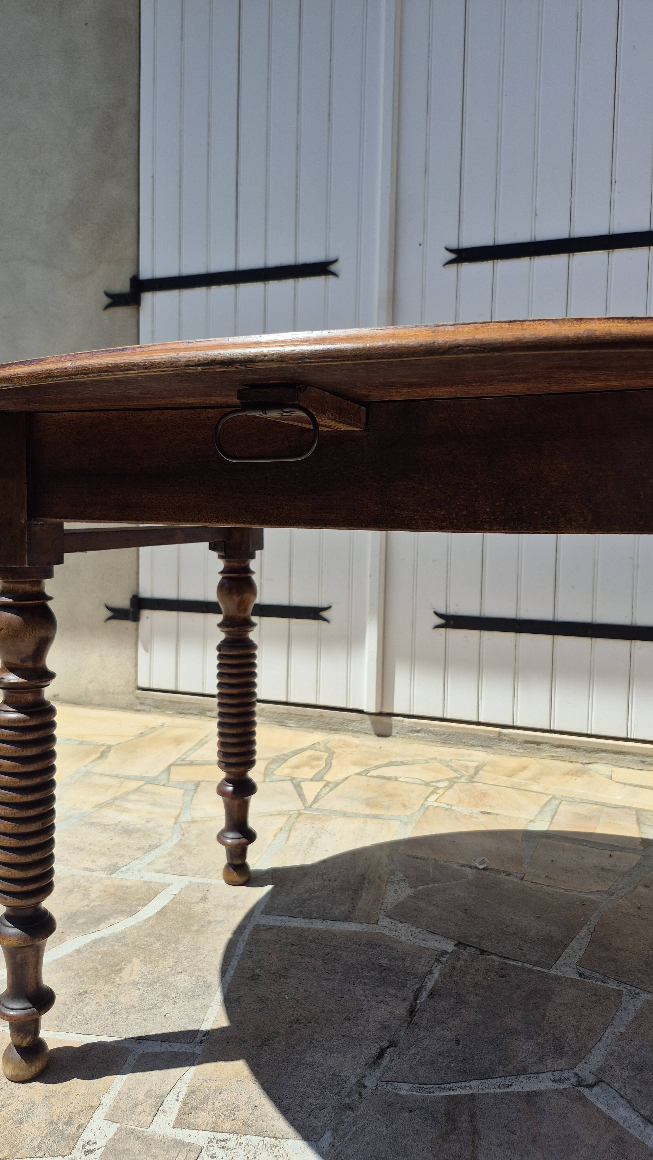 Round dining table with a drop-leaf top in solid walnut, late 19th century.