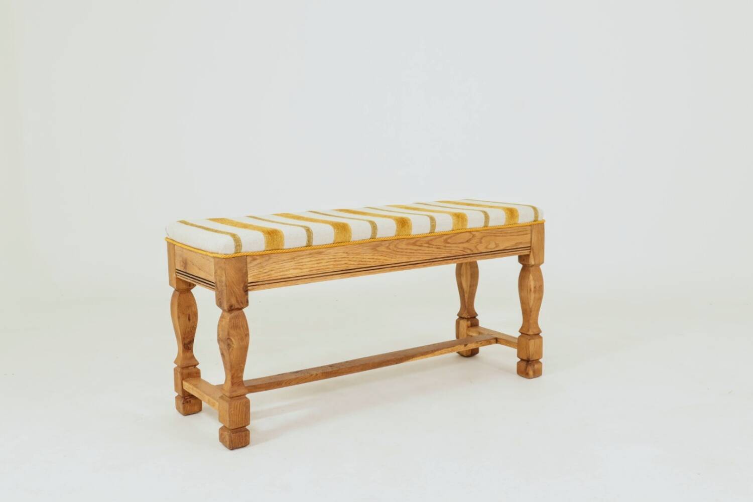 Vintage oak bench with striped linen fabric in a country style.
