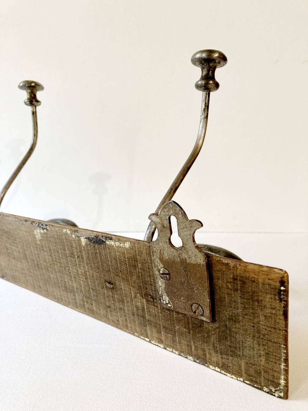 Pair of antique wrought iron coat hooks mounted on a wooden panel, 19th century