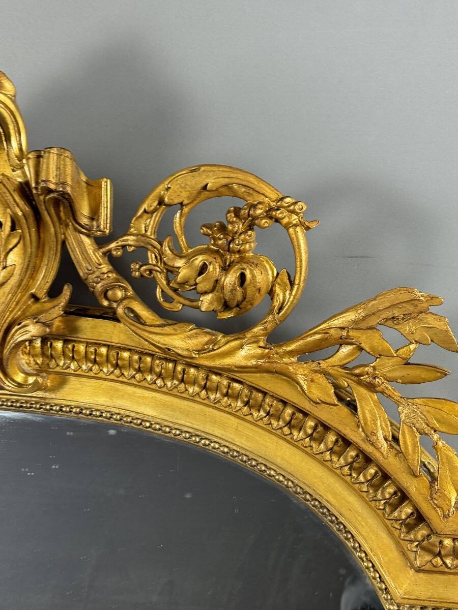 Large antique gilded wooden mirror in Louis XVI style with a sculpted pediment, 19th century.