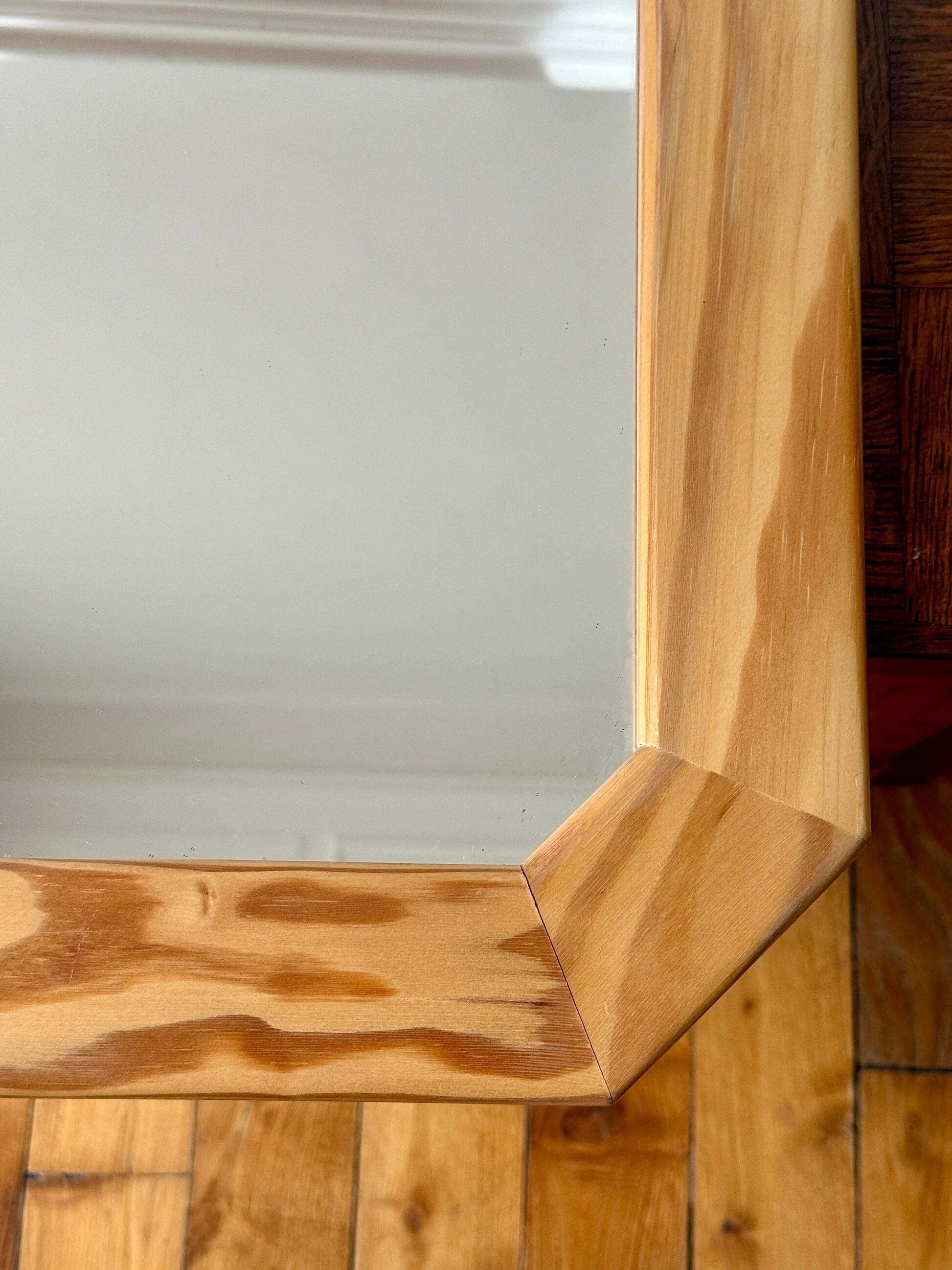 Octagonal mirror in light wood with grooves.