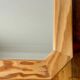 Octagonal mirror in light wood with grooves.