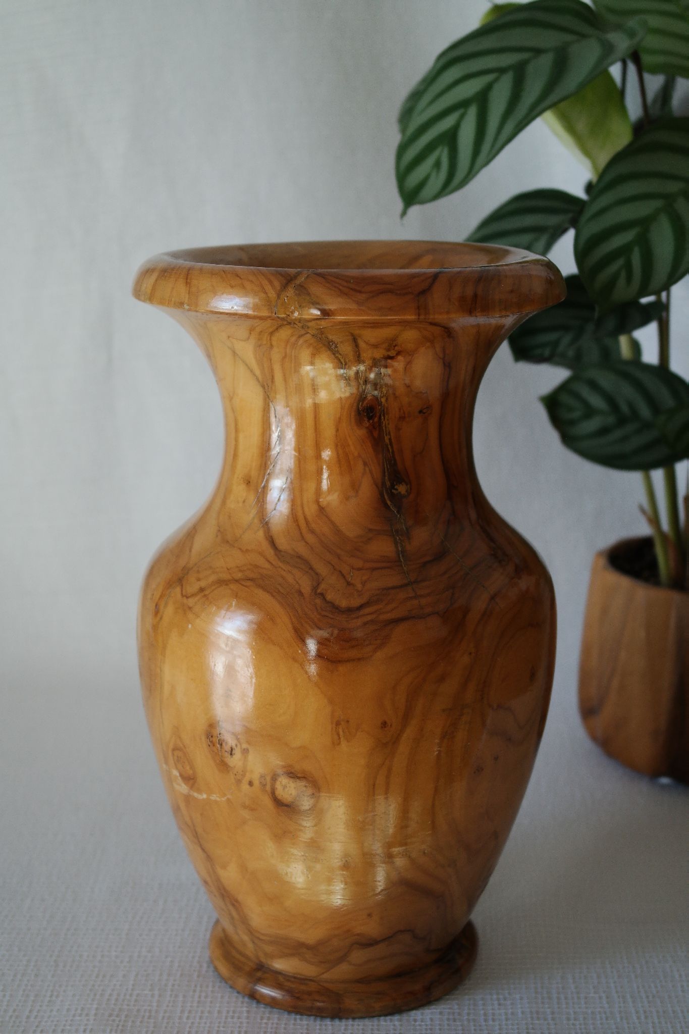 Artisanal turned olive wood vase with varnish.