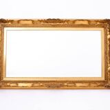 A mirror with a golden, richly carved frame.