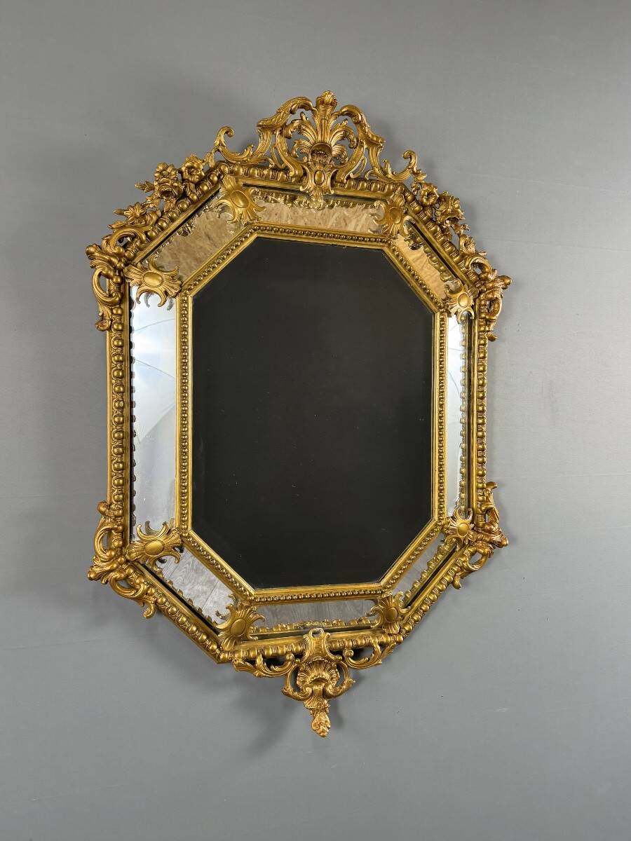 Antique octagonal mirror in richly carved gilded wood, Louis XV style.