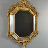 Antique octagonal mirror in richly carved gilded wood, Louis XV style.