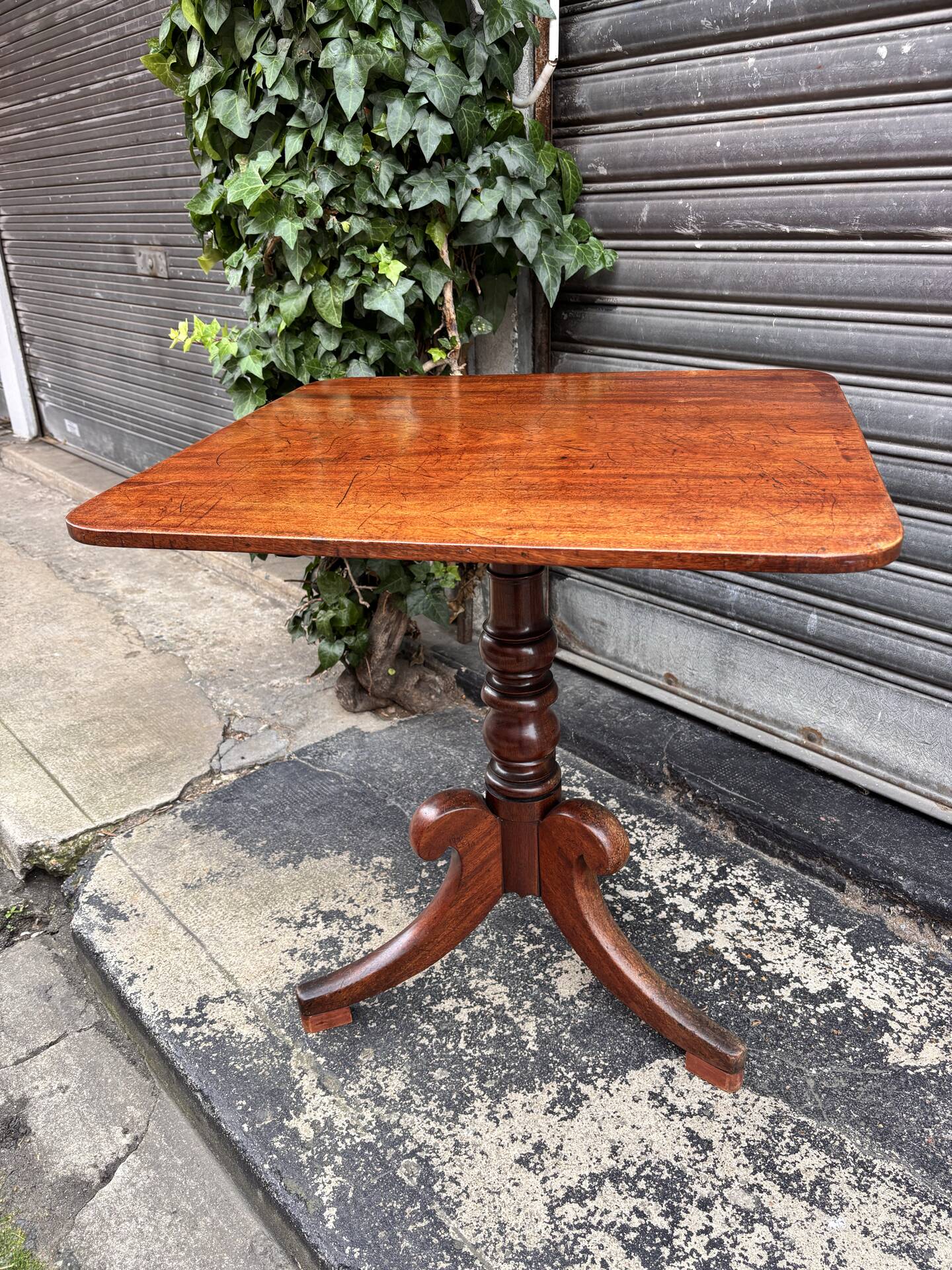 19th-century solid mahogany table with a tilting top and brass mechanism.