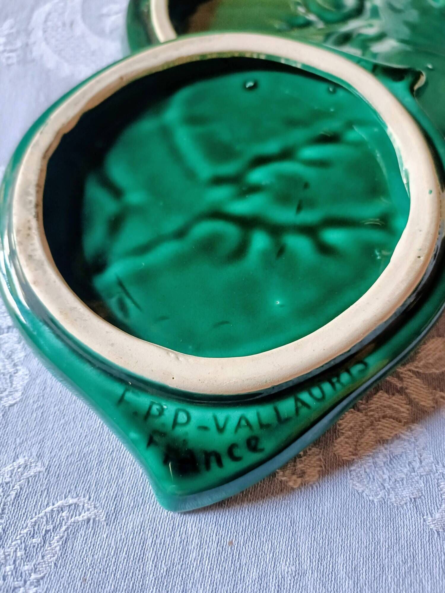 A trivet and two bottle holders in green Vallauris majolica.