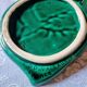 A trivet and two bottle holders in green Vallauris majolica.