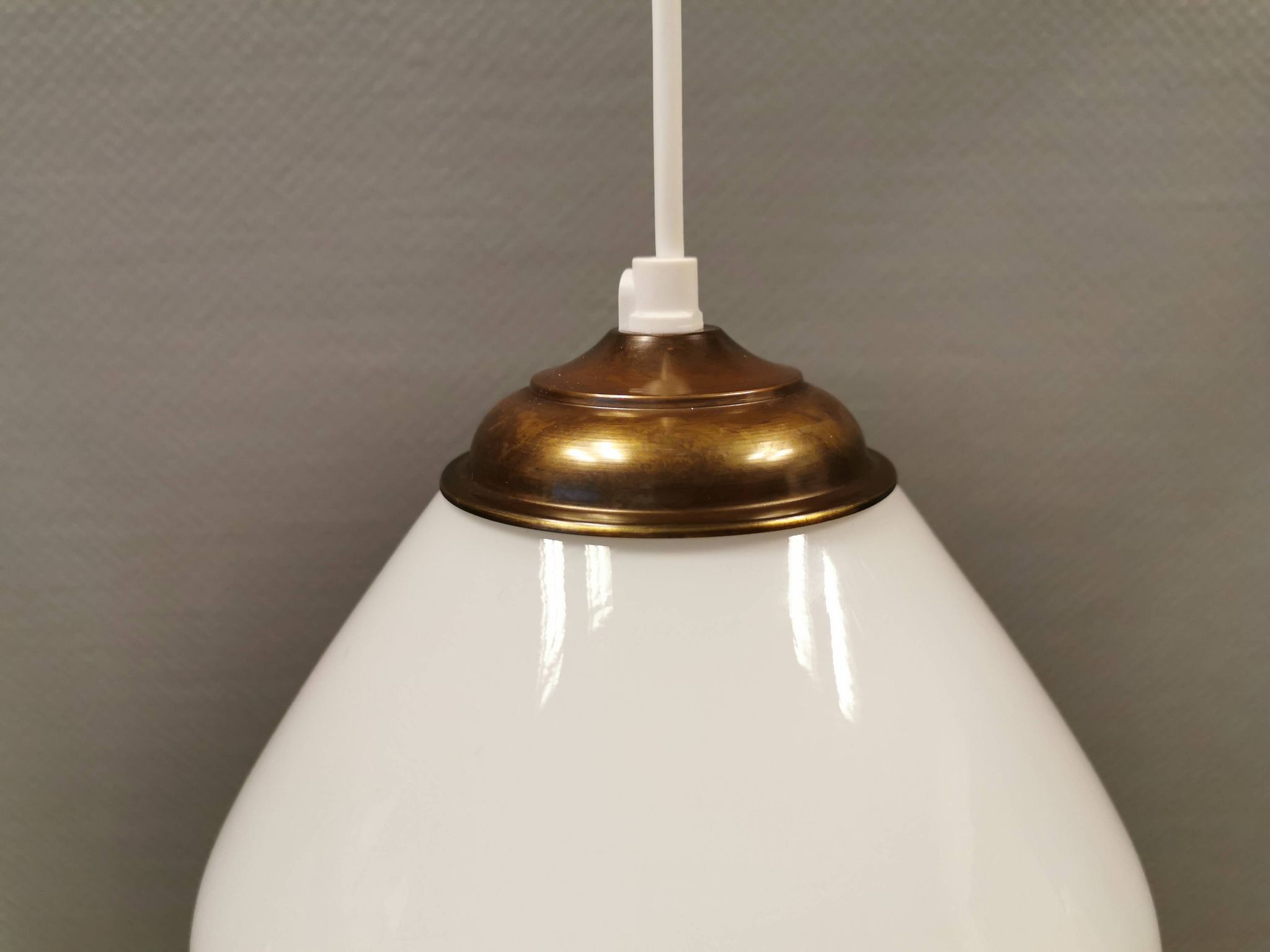 Beautiful ball-shaped hanging lamp in white opal glass with brass top.