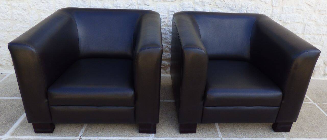 2 club armchairs with a chocolate faux leather seat and backrest and wooden legs.