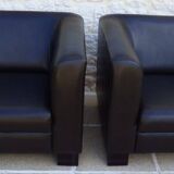 2 club armchairs with a chocolate faux leather seat and backrest and wooden legs.