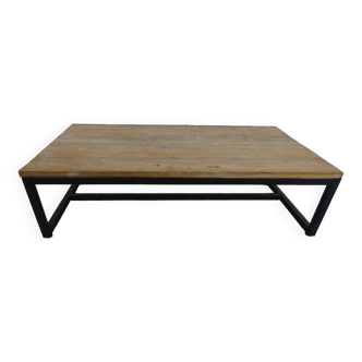 Industrial style coffee table with wooden top supported by a metal base -