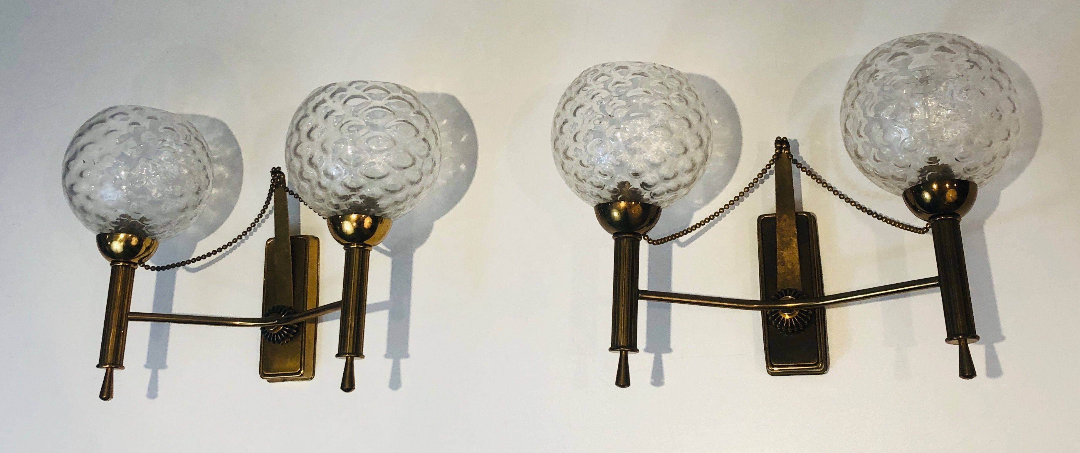 Pair of brass wall lights with glass globes. Around 1970.