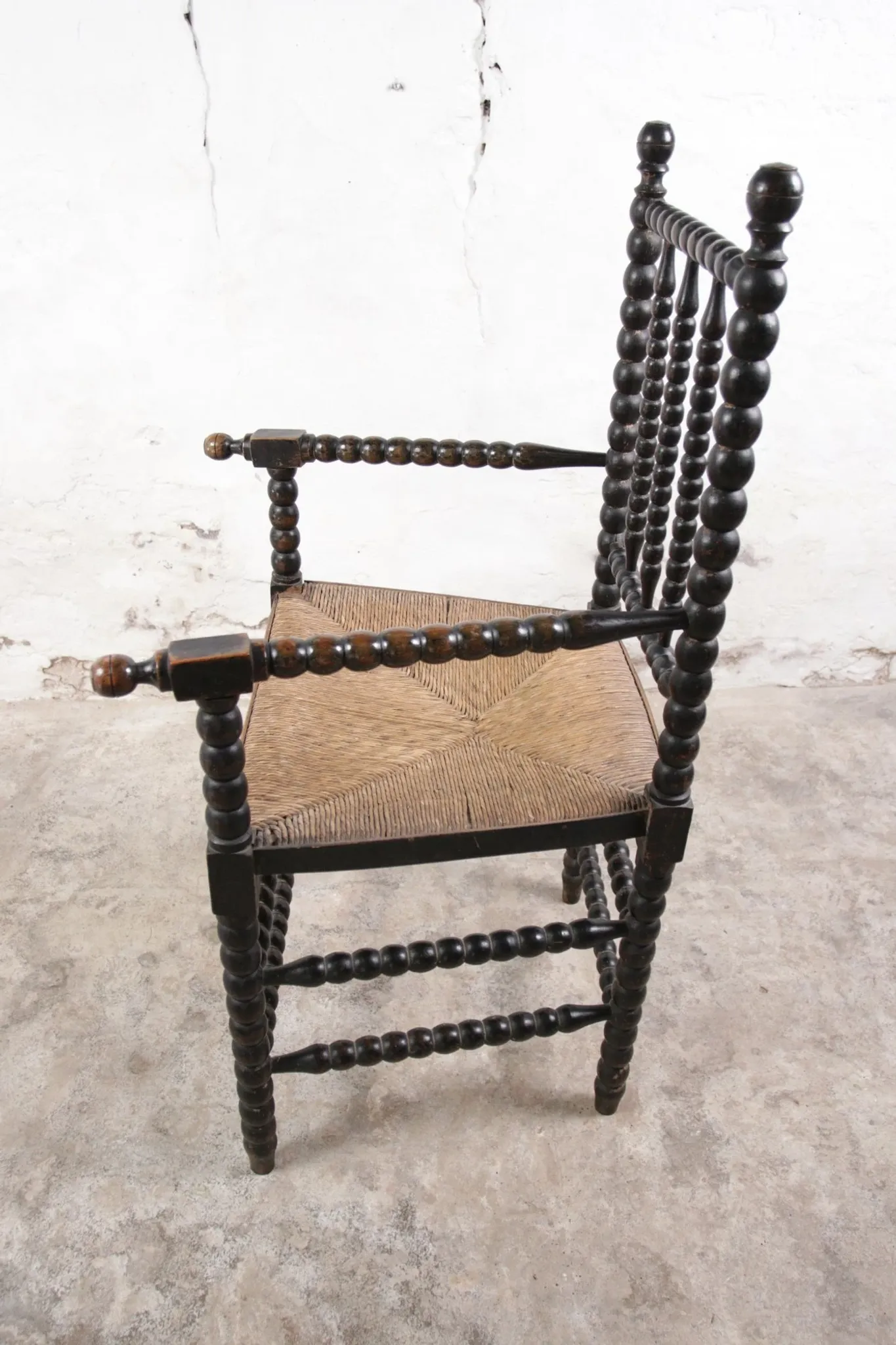 Black bobbin chair with armrests and rush seat – ca. 1900-1930