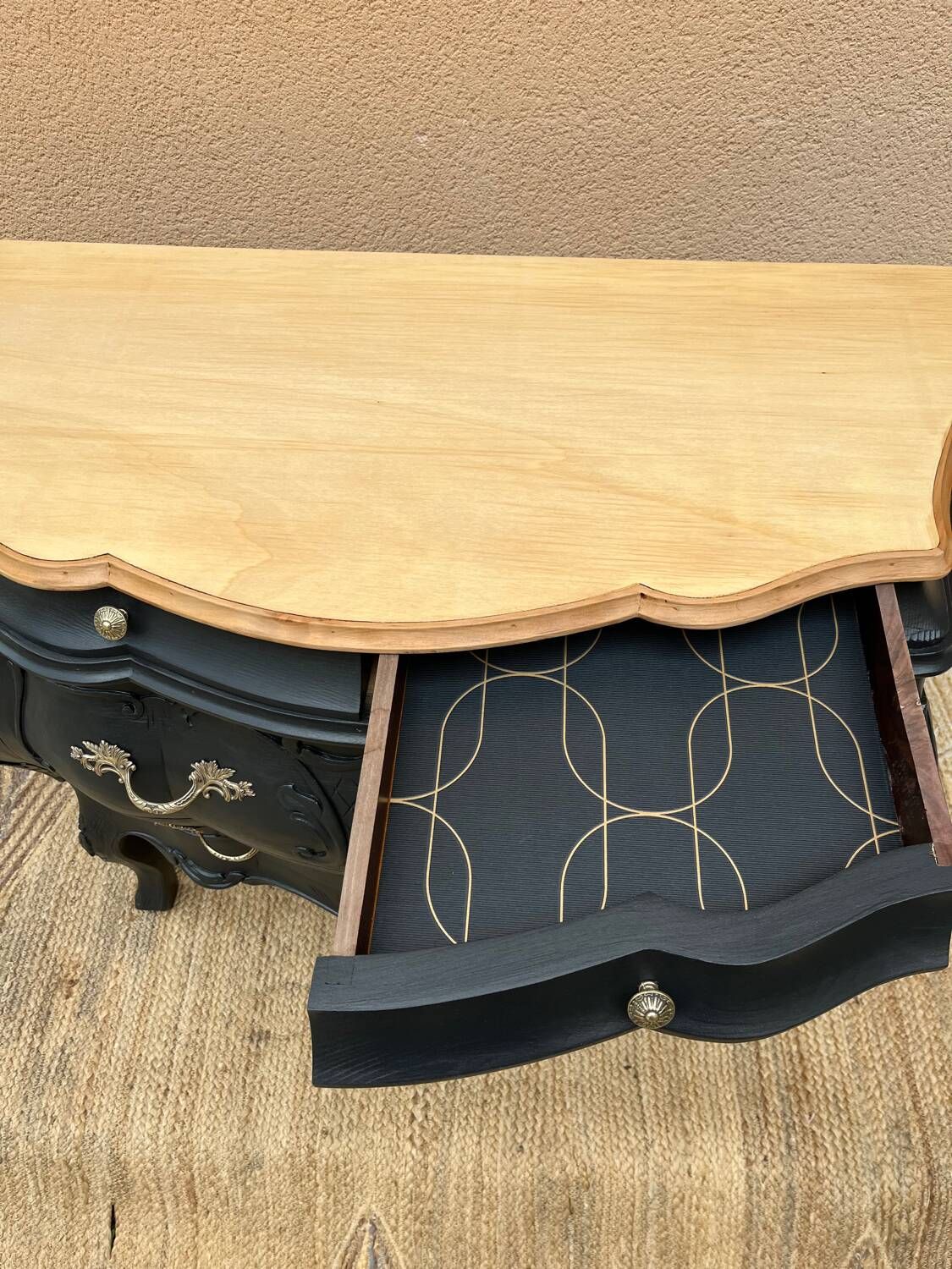 Curved commode painted in black and wood.