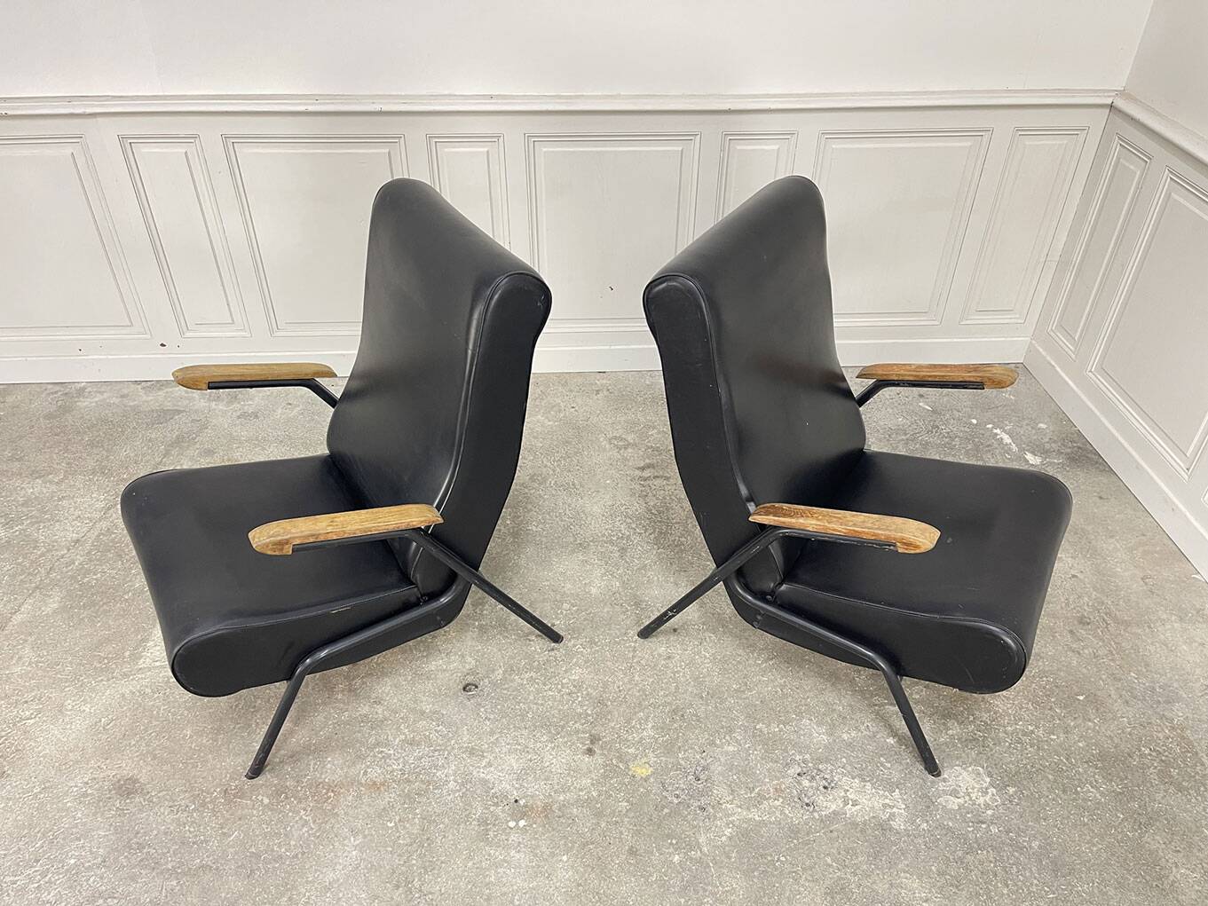 A pair of vintage armchairs in black faux leather.
