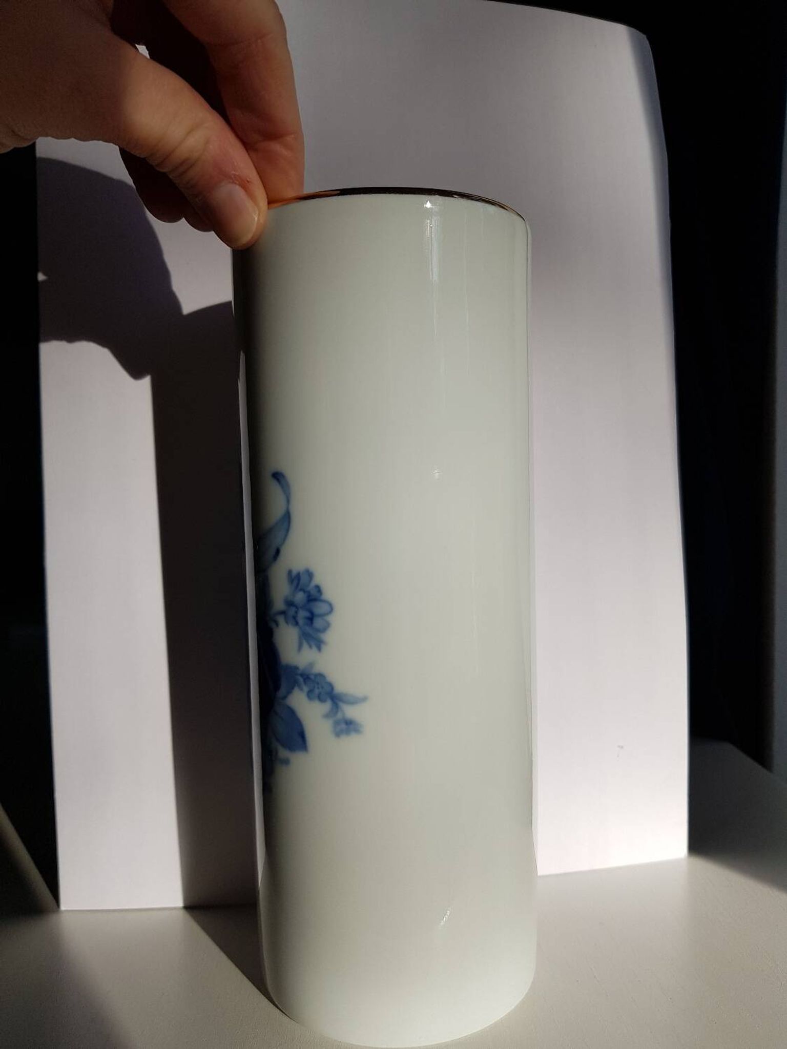 White porcelain vase from Limoges with blue decoration and gold rim.