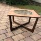 Round glass coffee table with a gold border and brown teak structure, Astro 1960s style.
