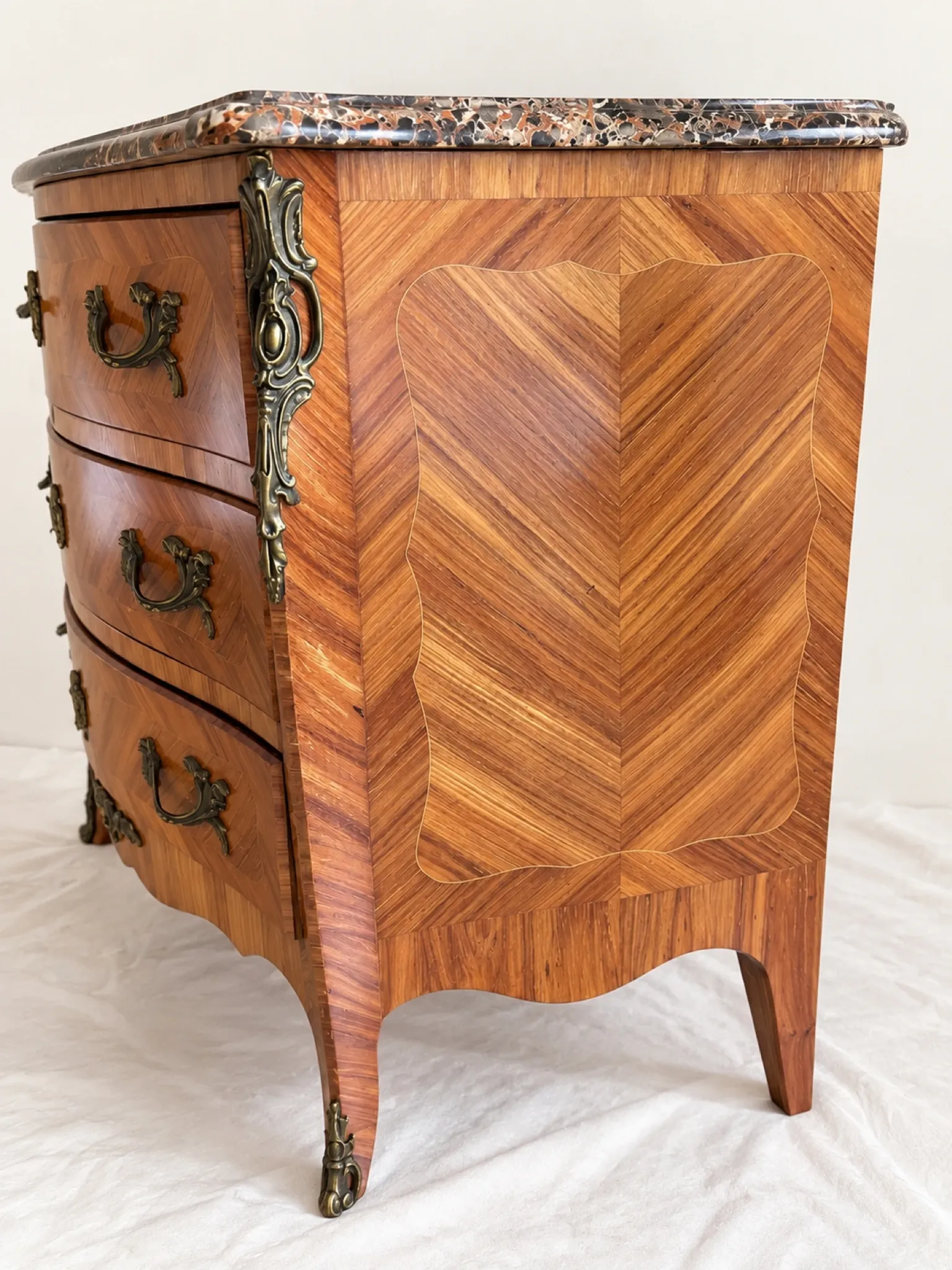 Curved Louis XV style commode in marquetry, veined marble and ornamentation.