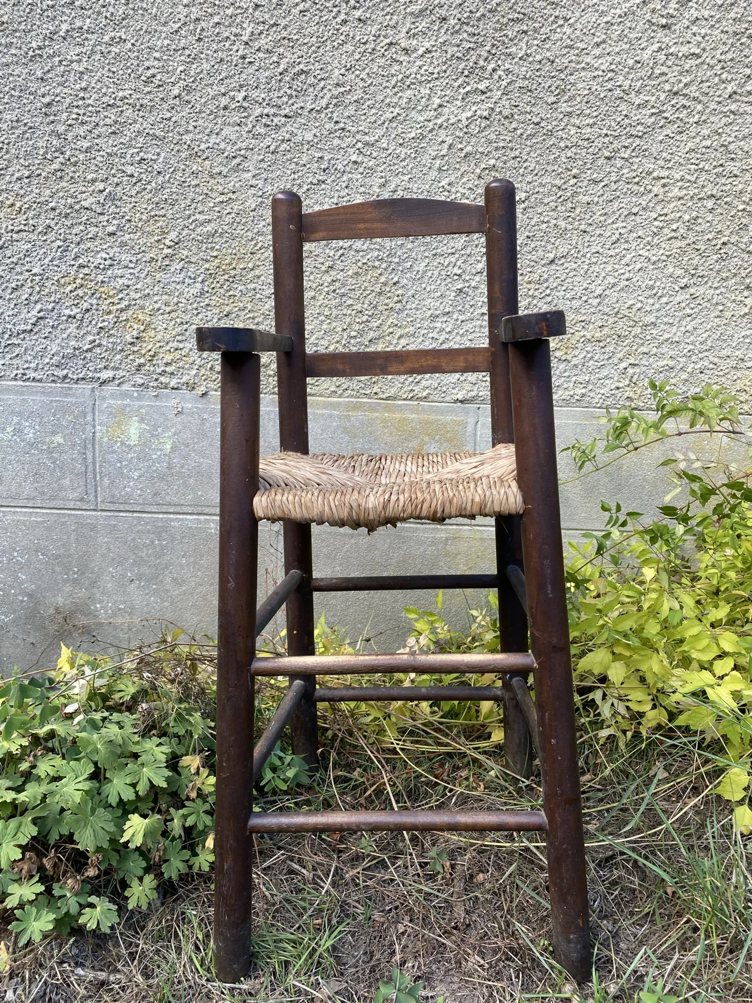 Vintage wooden children's high chair with straw.