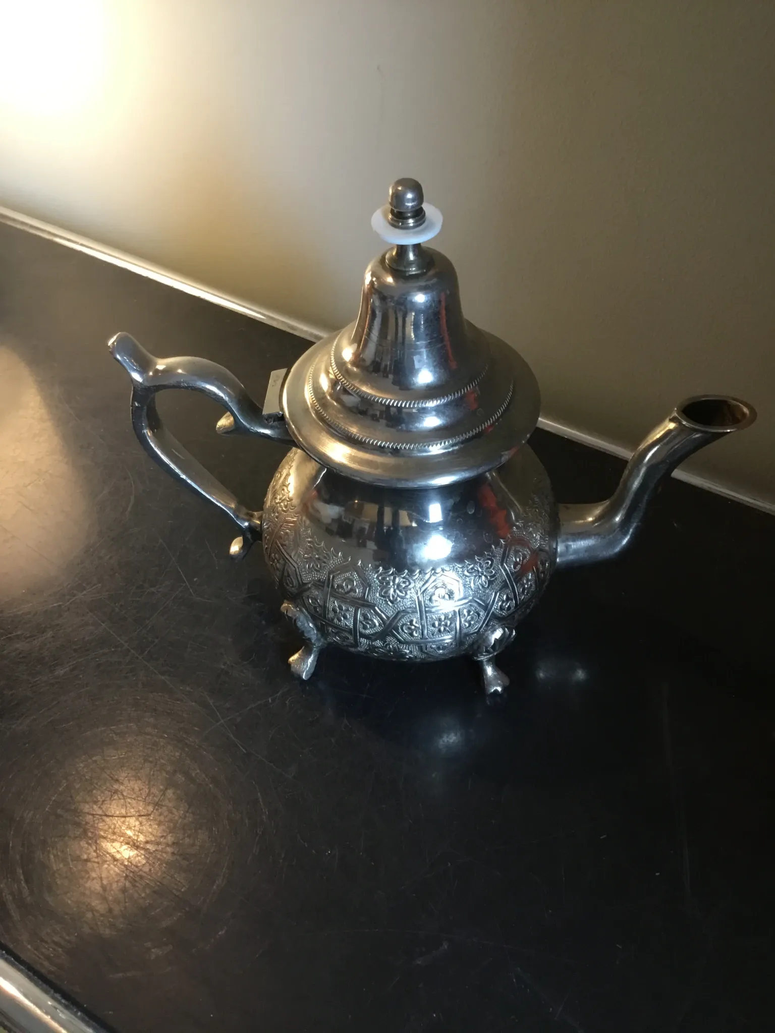 Traditional metal teapot with silver plating, Eastern style, on a stand.