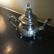 Traditional metal teapot with silver plating, Eastern style, on a stand.