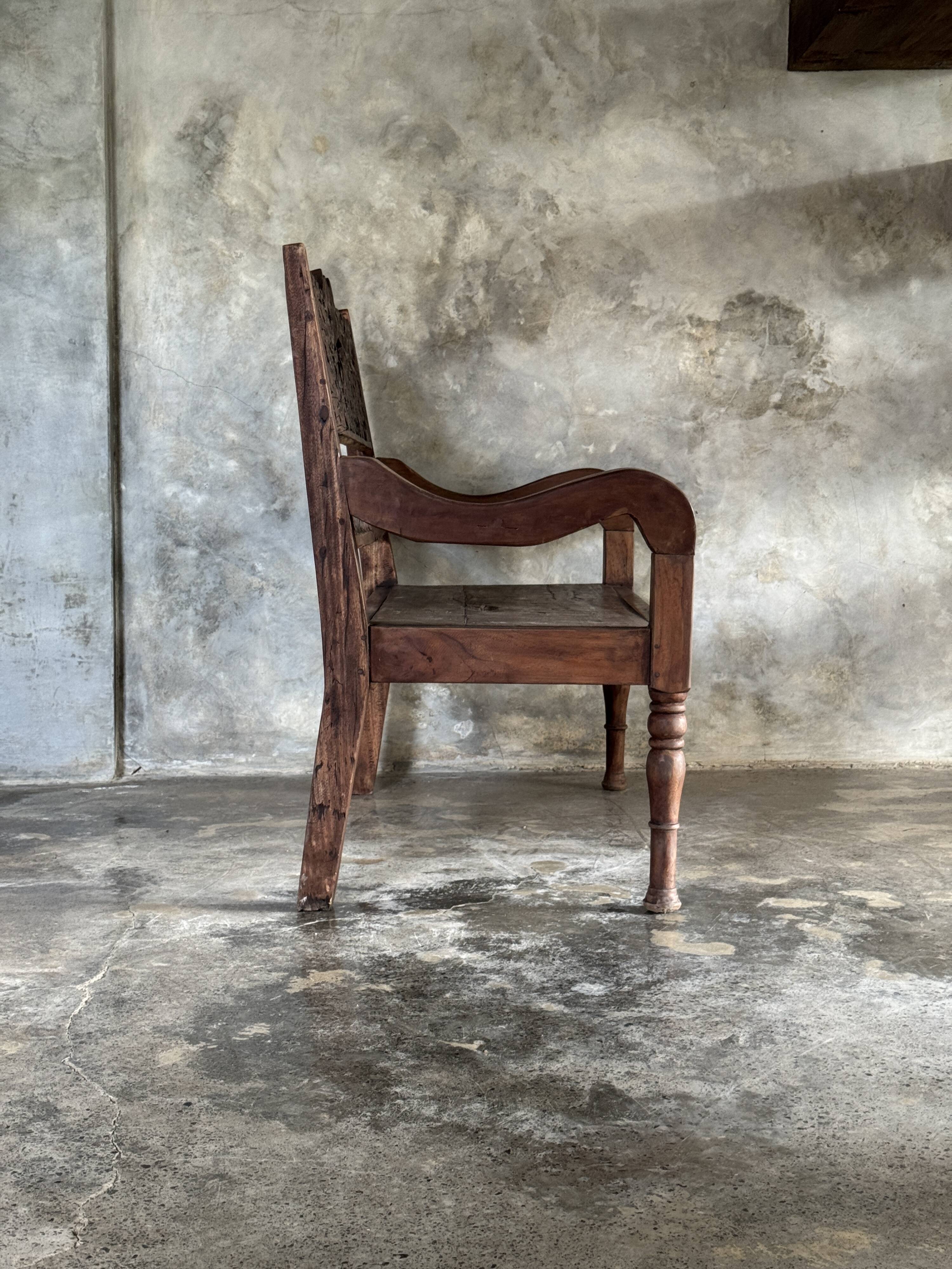 Small antique Indonesian bench in carved teak with plant and floral motifs.