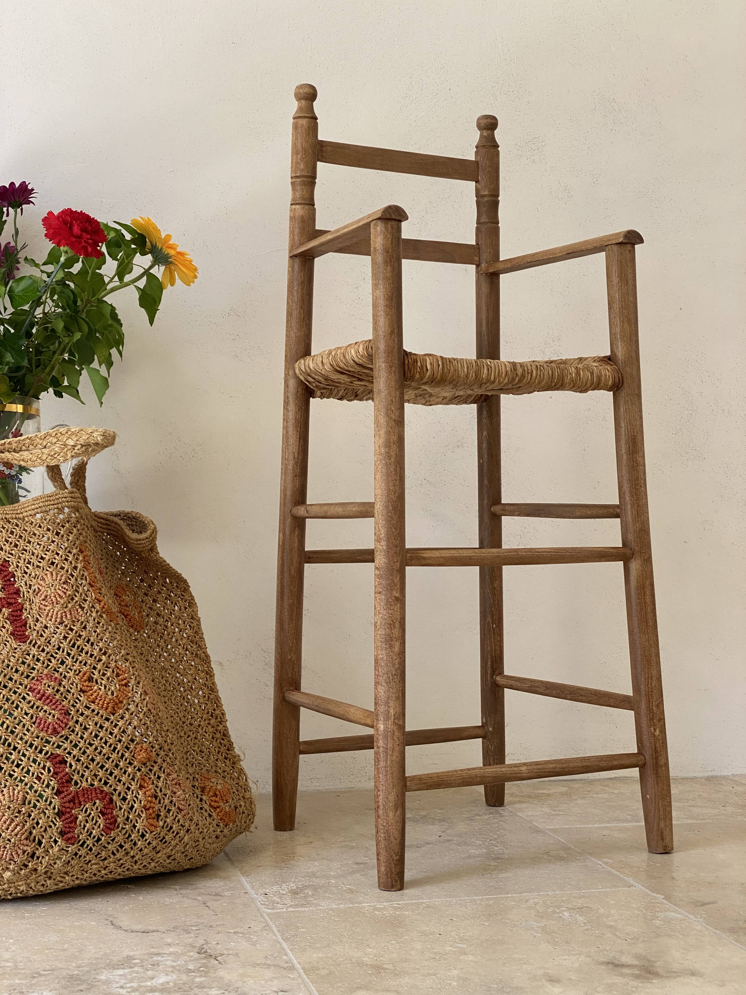 Old wooden high chair for children with a straw seat.
