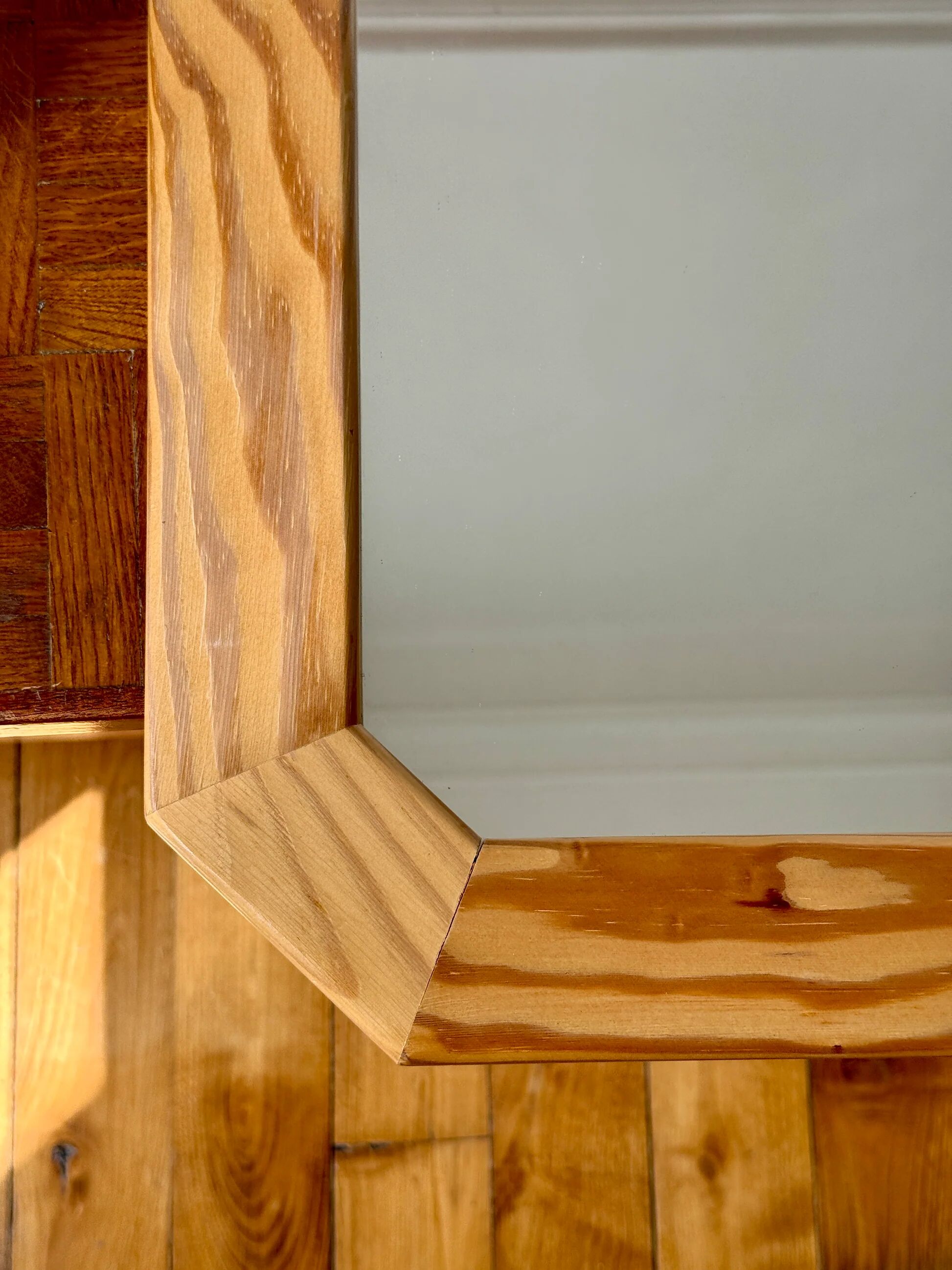 Octagonal mirror in light wood with grooves.