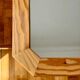 Octagonal mirror in light wood with grooves.