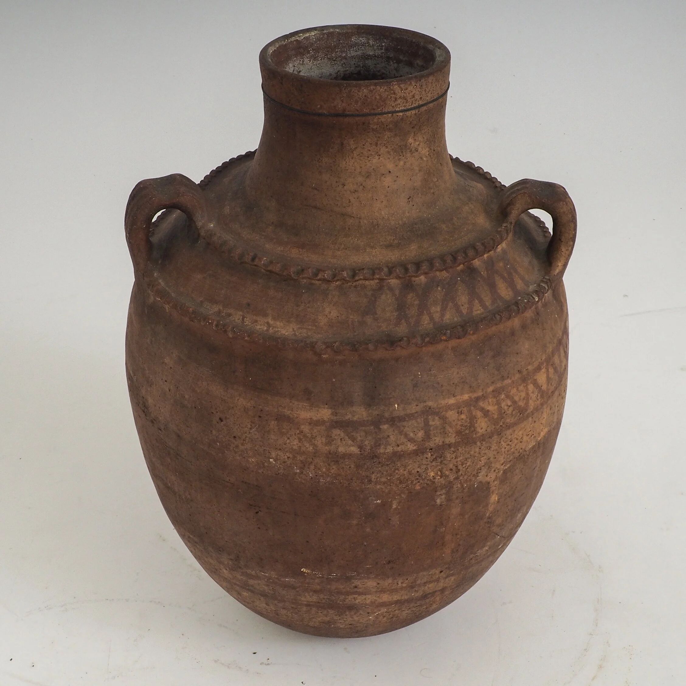 Vaisseau en terre cuite primitive avec des détails géométriques peints à la main.