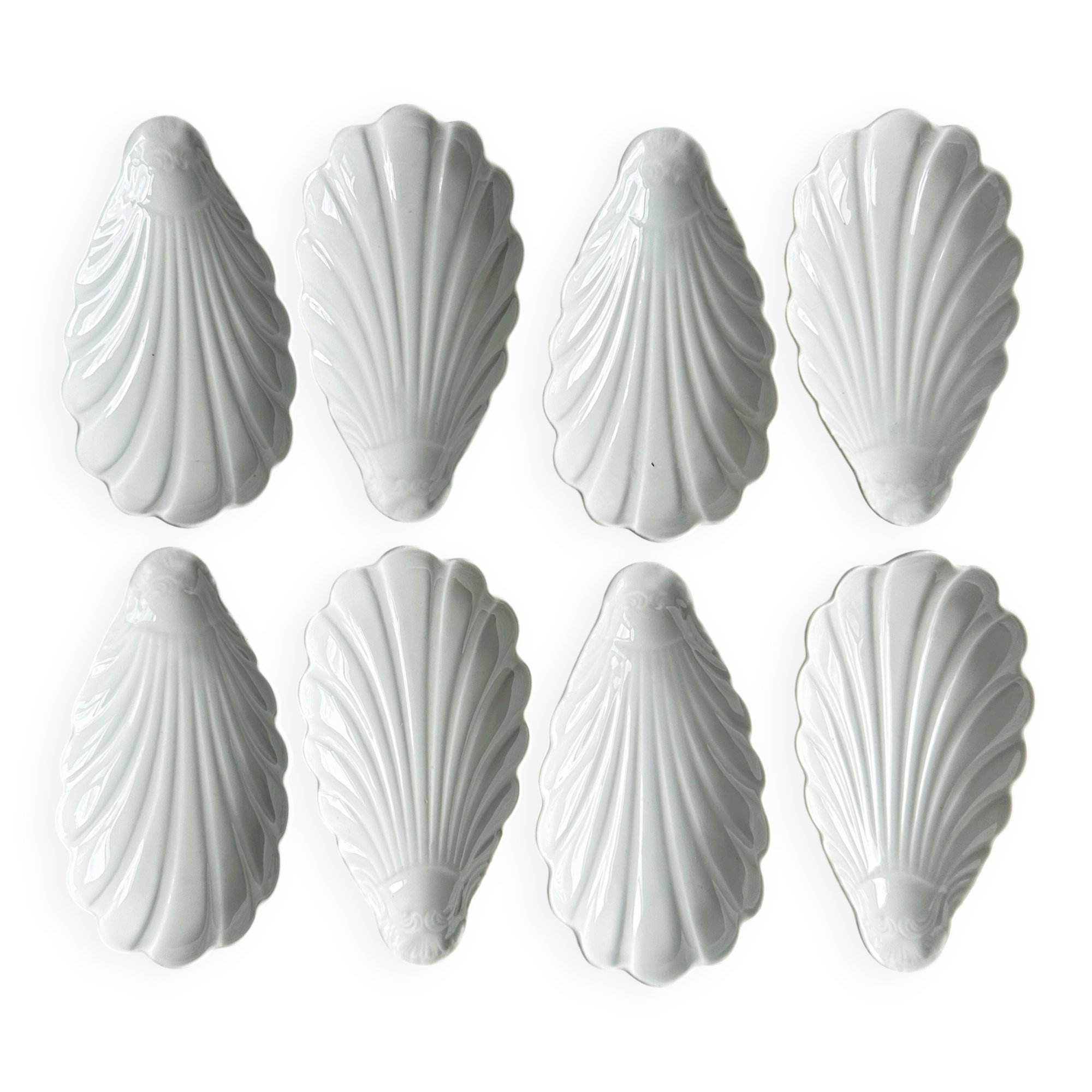 Set of white porcelain ramekins, ribbed shell shape.