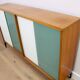 A vintage mid-century bookshelf/sideboard with green and white sliding door