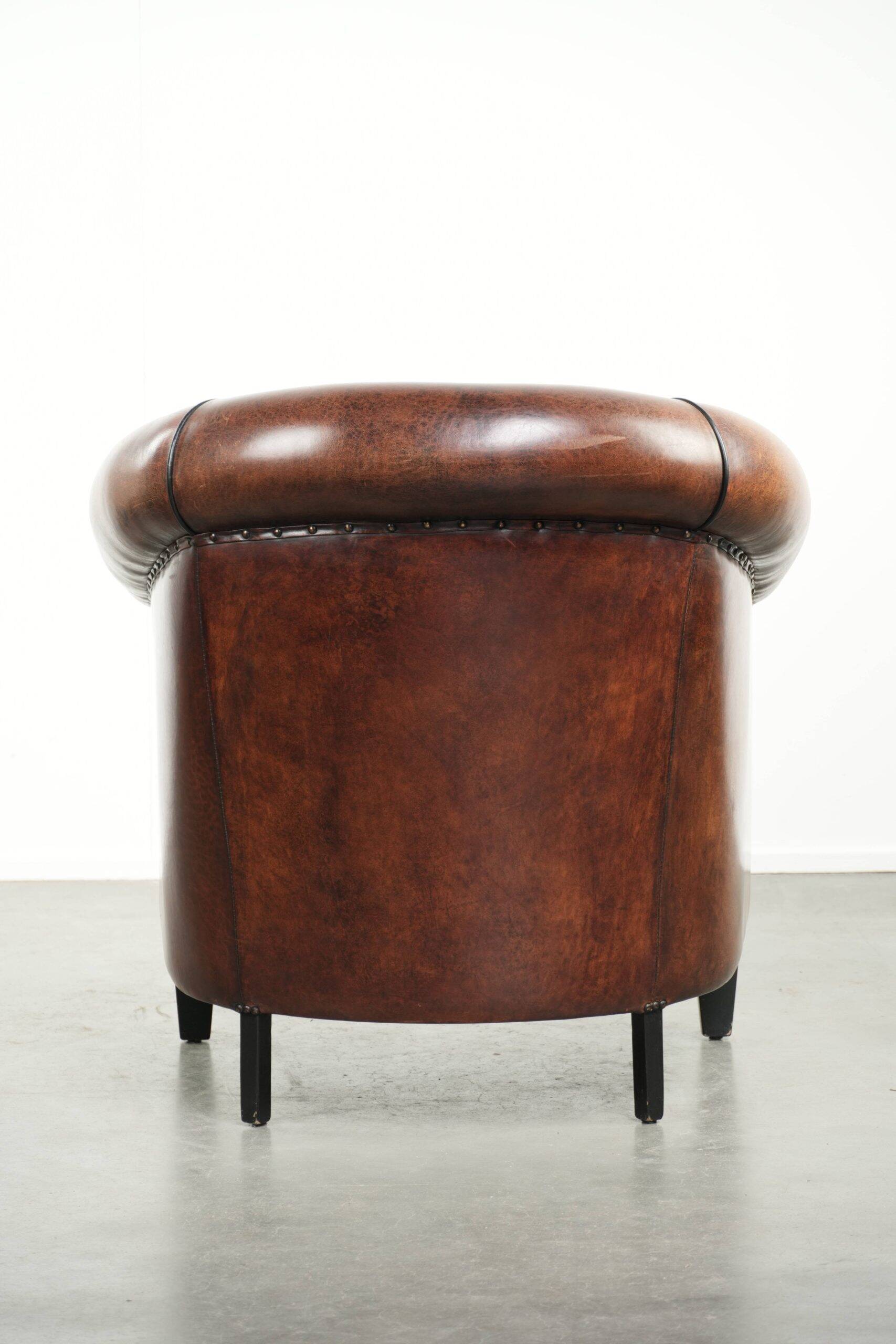 Sheepskin club armchair with deep warm colours and black piping