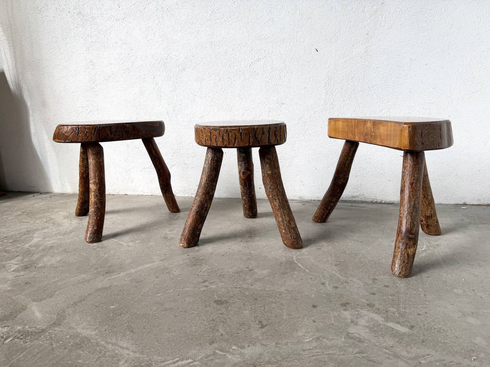 Set of three rustic solid wood tripod stools.