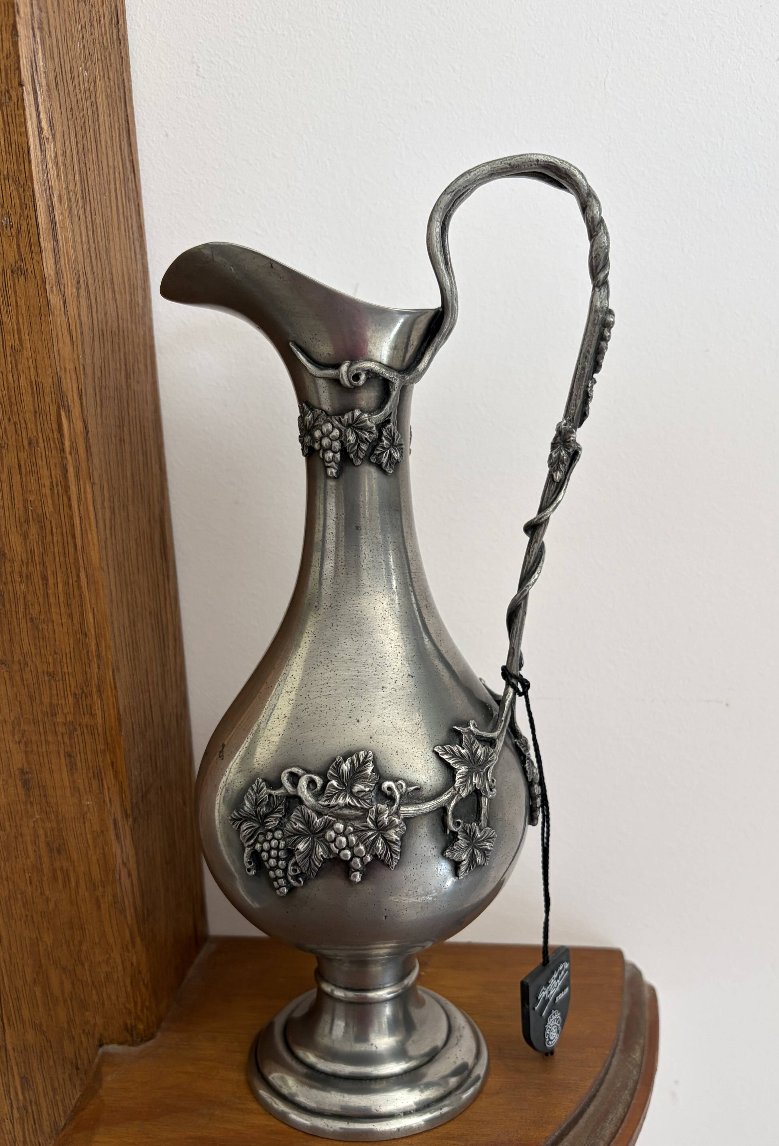 Ewer in pewter surrounded by vine branches with g