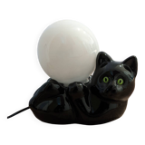 Black cat playing with its globe table lamp