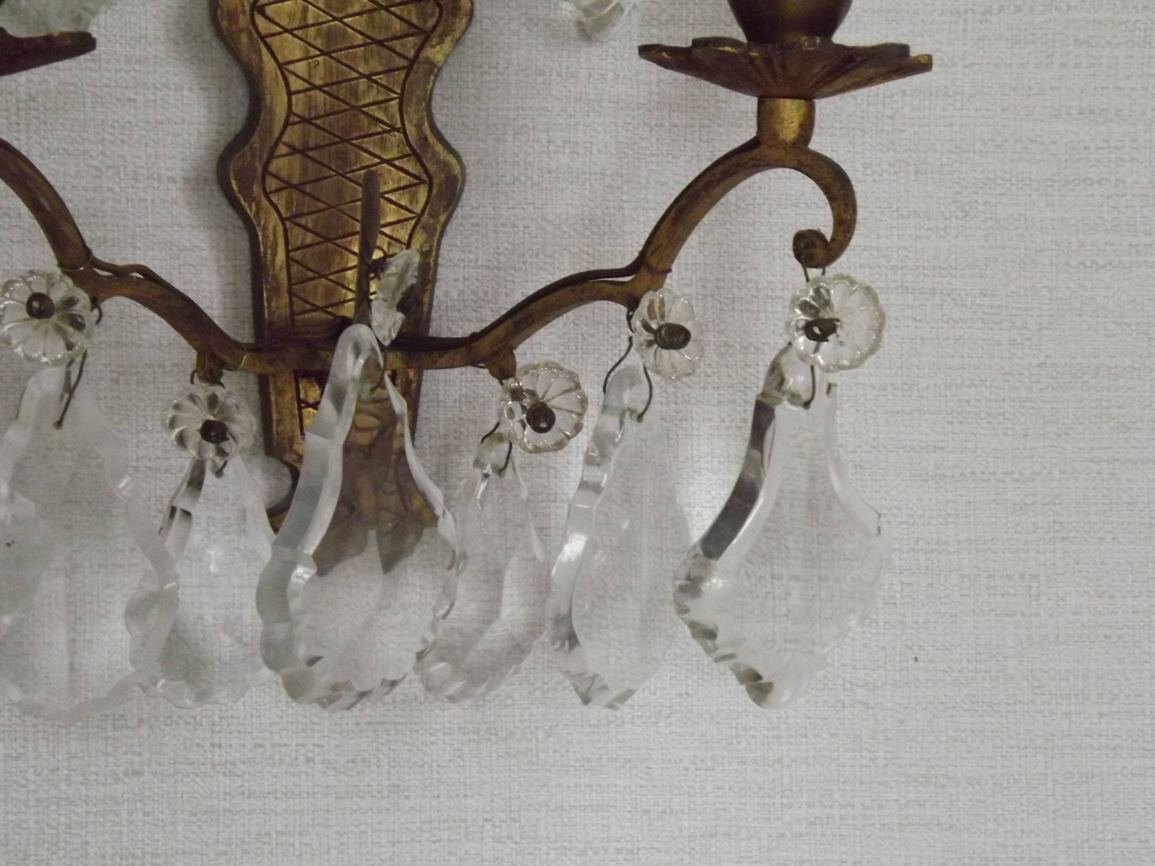 Pair of French antique brass double wall lights with assorted crystals.