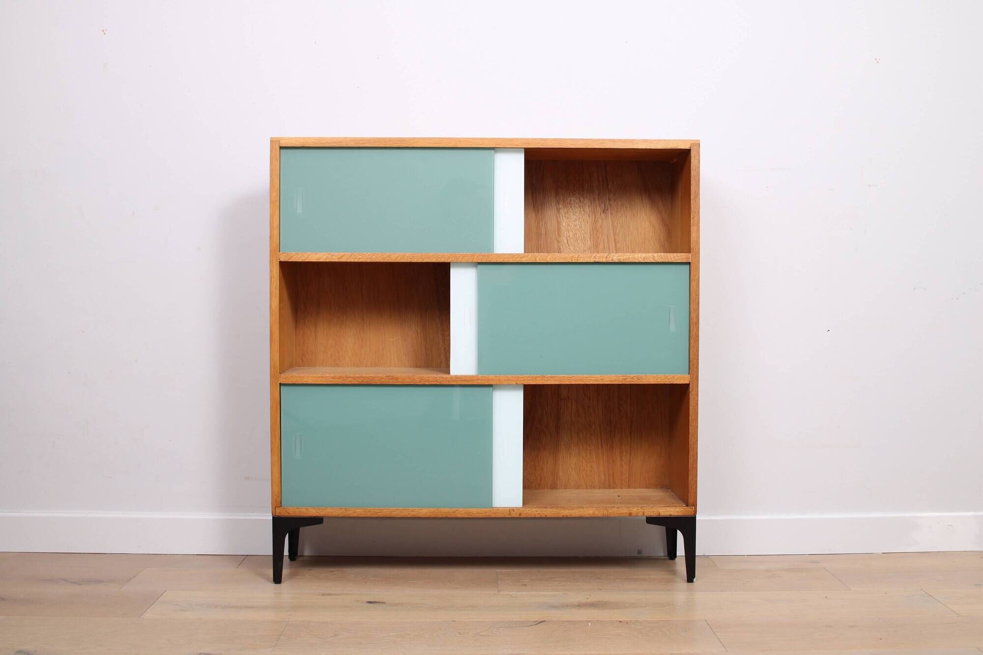 A vintage mid-century 3 tiered bookcase with glass sliding doors