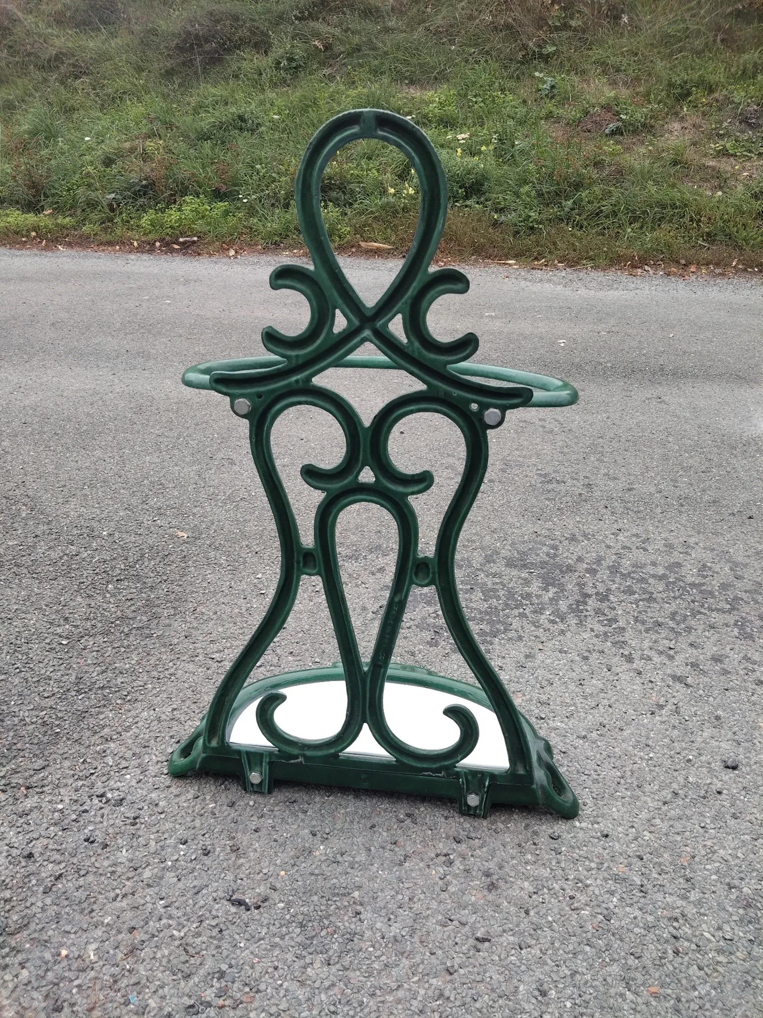 Bottle green enamelled cast iron umbrella stand with a swirl design.