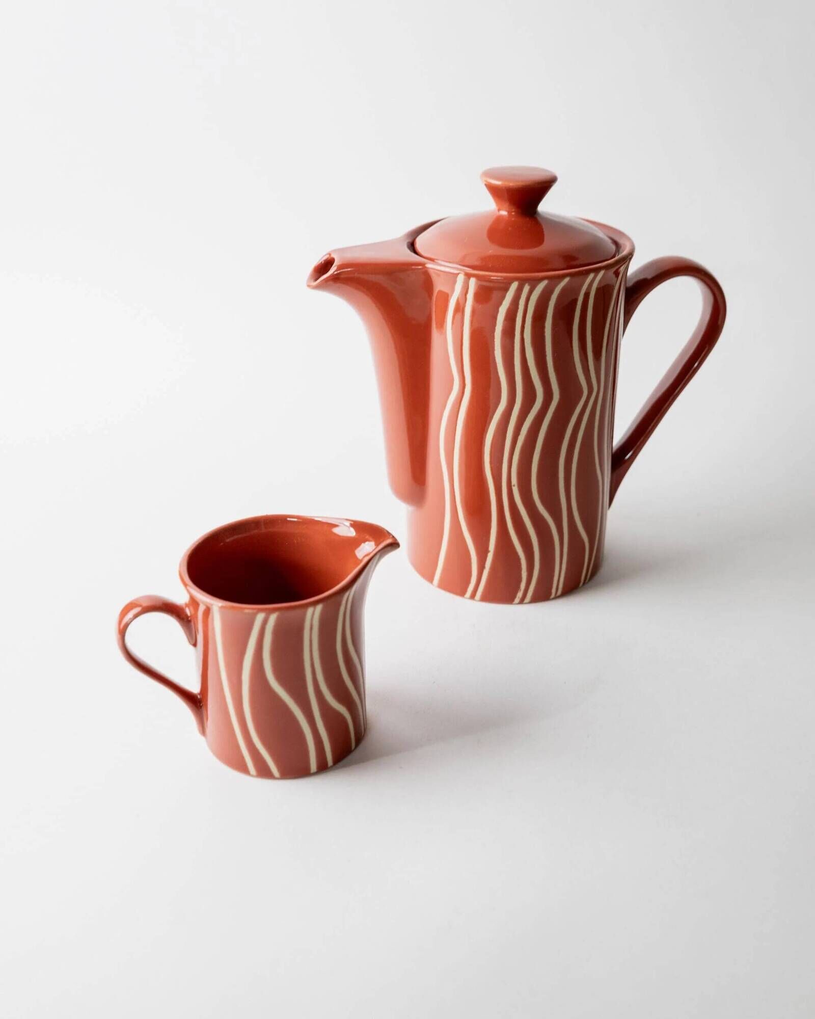 Vintage tea or coffee service in 1970s ceramic, teapot with lid and milk jug, rust orange with retro striped pattern, mid-century decoration, gift idea.