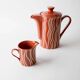 Vintage tea or coffee service in 1970s ceramic, teapot with lid and milk jug, rust orange with retro striped pattern, mid-century decoration, gift idea.