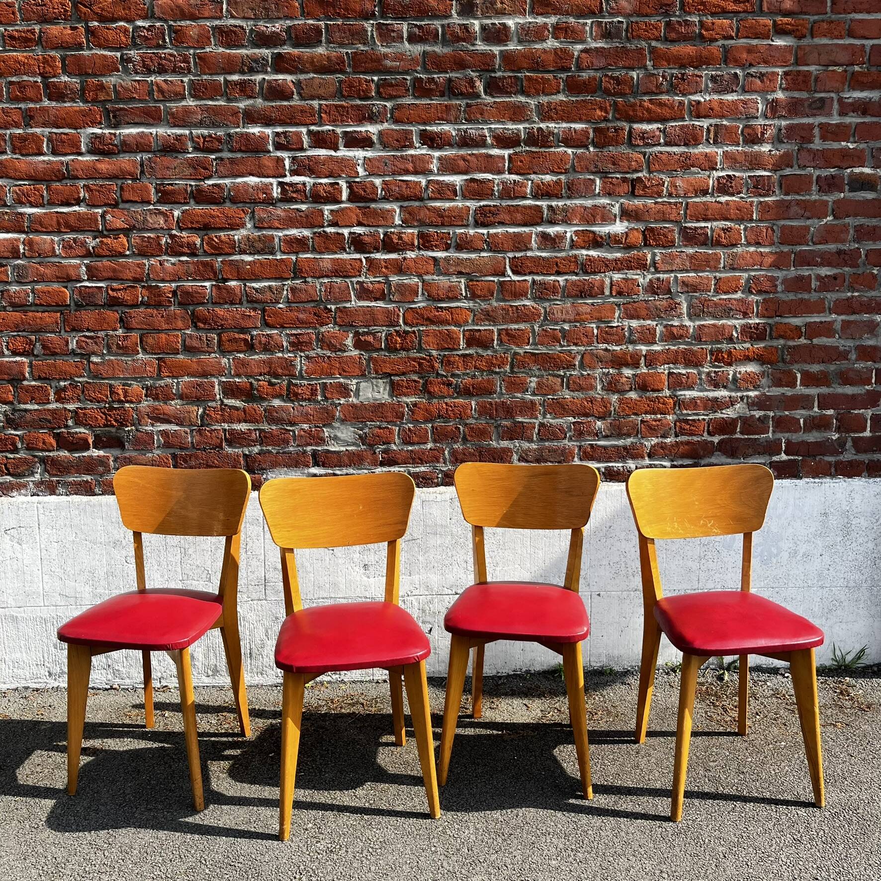 Set of 4 vintage bistro chairs in wood and red faux leather, with splayed legs.